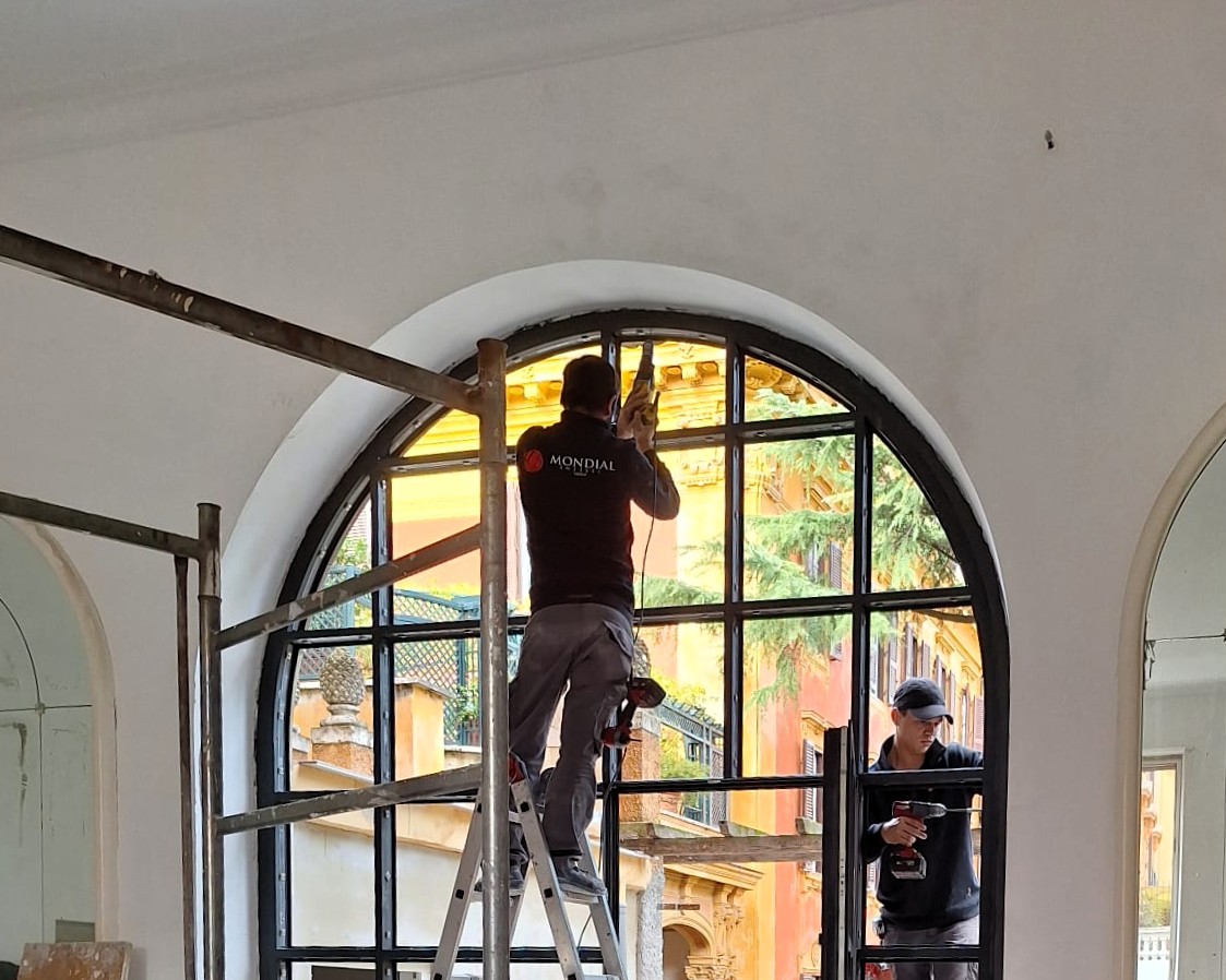 Maestranze al lavoro sulla grande vetrata centinata