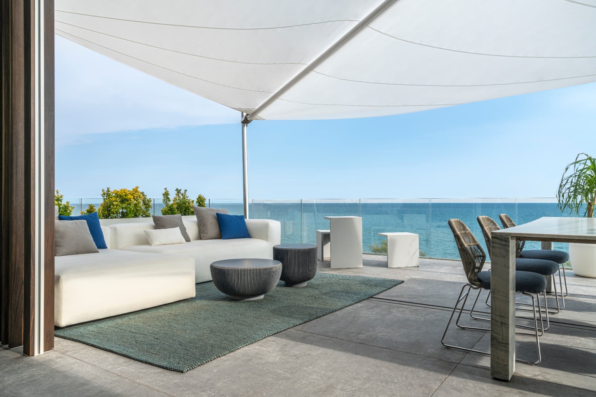 Terrazza con tenda a vela e arredi bianchi sul mare