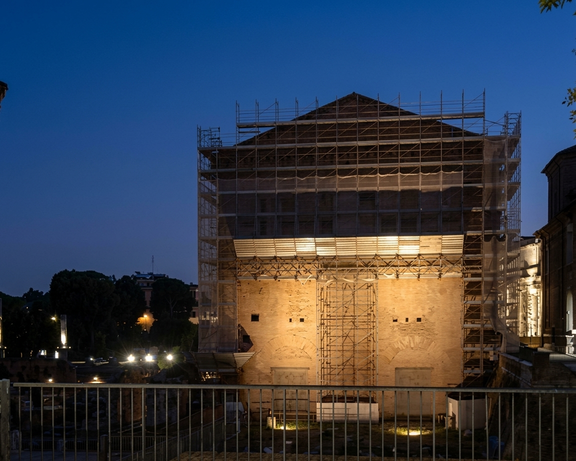 Il ponteggio illuminato sulla Curia Iulia all'imbrunire