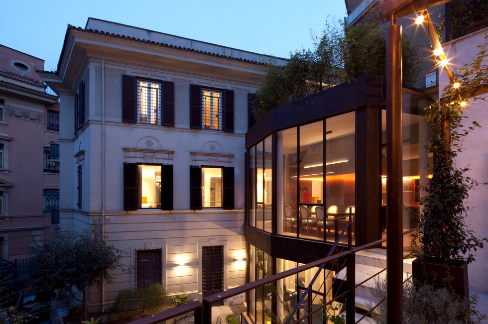 La vetrata in acciaio corten di Casa Trastevere illuminata al tramonto
