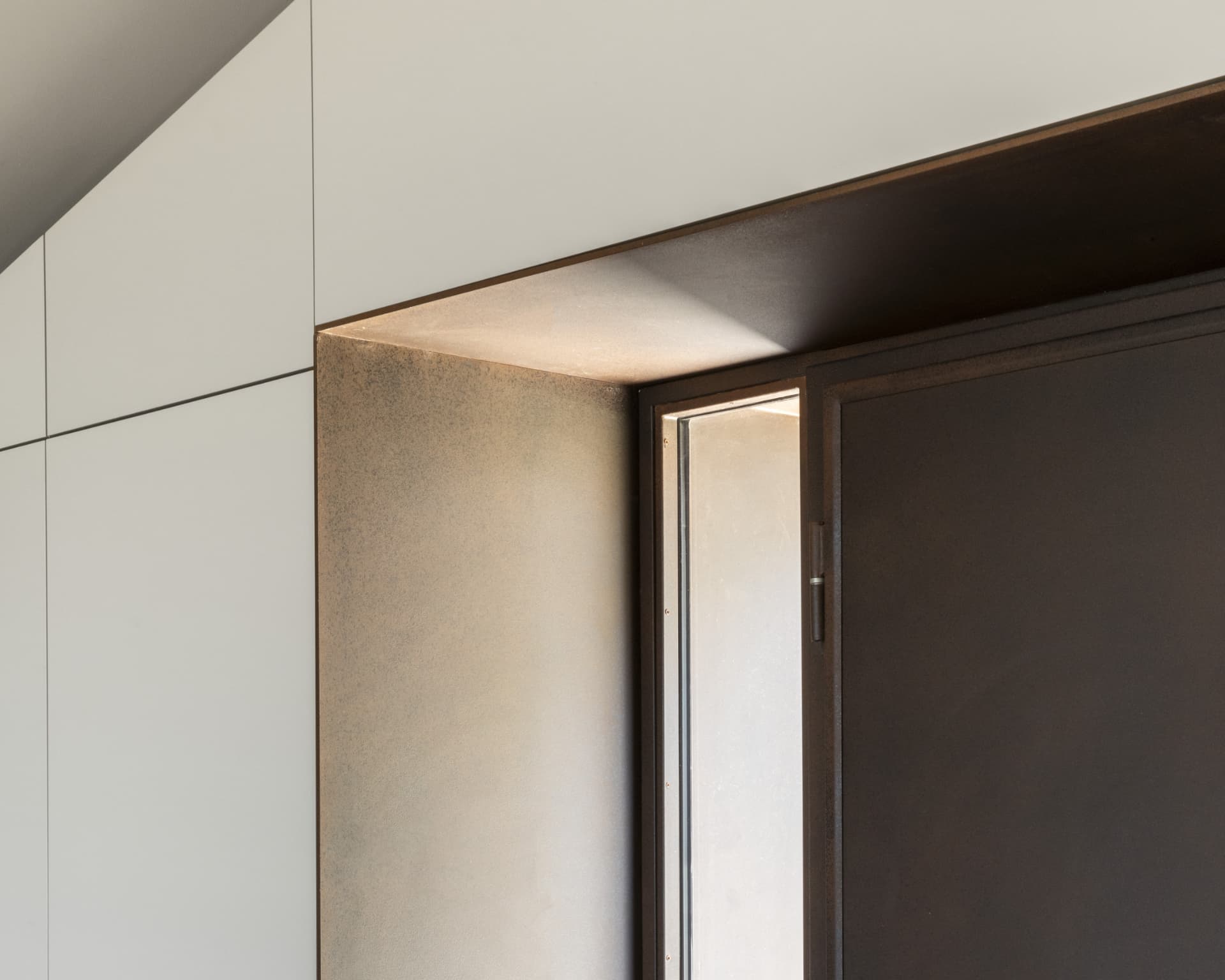 Dettaglio di porta in acciaio corten e luce radente