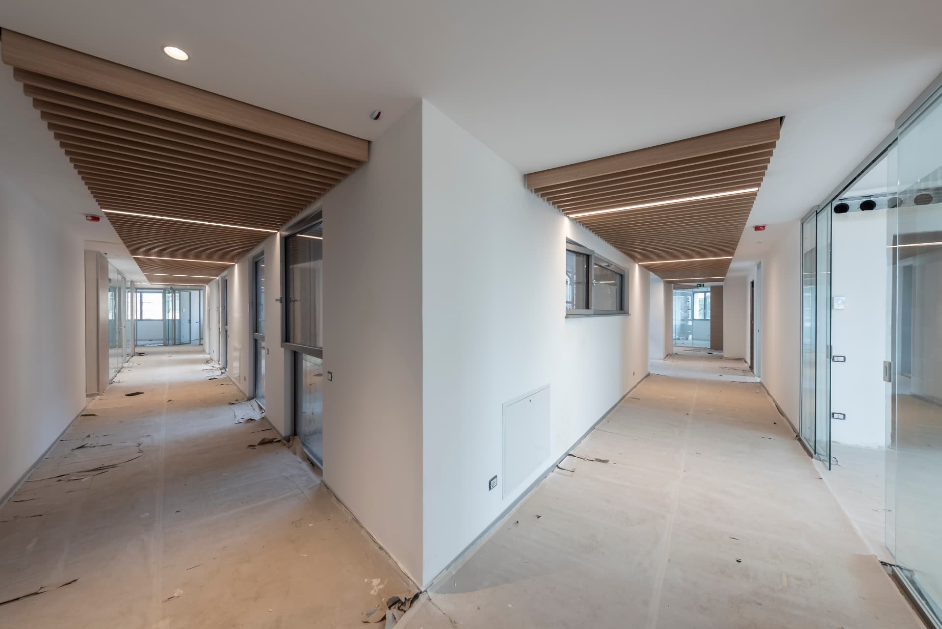 Corridoio interno con controsoffitto in doghe di legno e vetrate