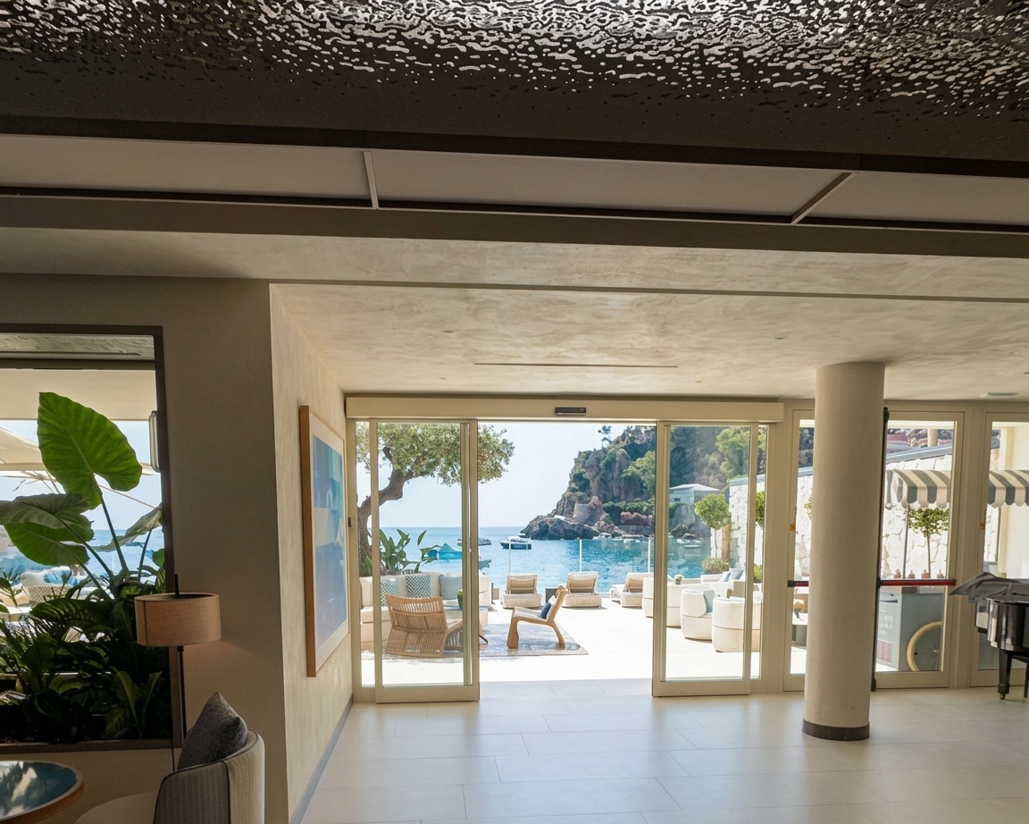 La hall con le vetrate aperte verso la terrazza sul mare